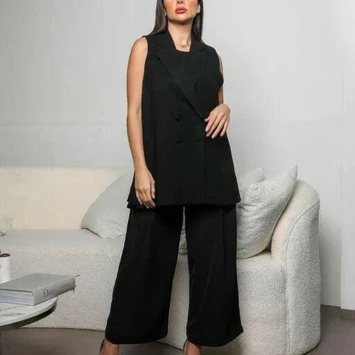 Woman wearing sleeveless black crepe double-breasted vest with sharp lapel collar styled with black wide-leg trousers in modern room - black crepe vest