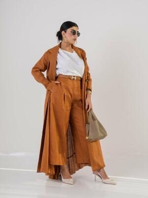 Woman wearing elegant orange blazer abaya made of lightweight linen with classic lapel collar and button details, styled with sunglasses and beige heels.