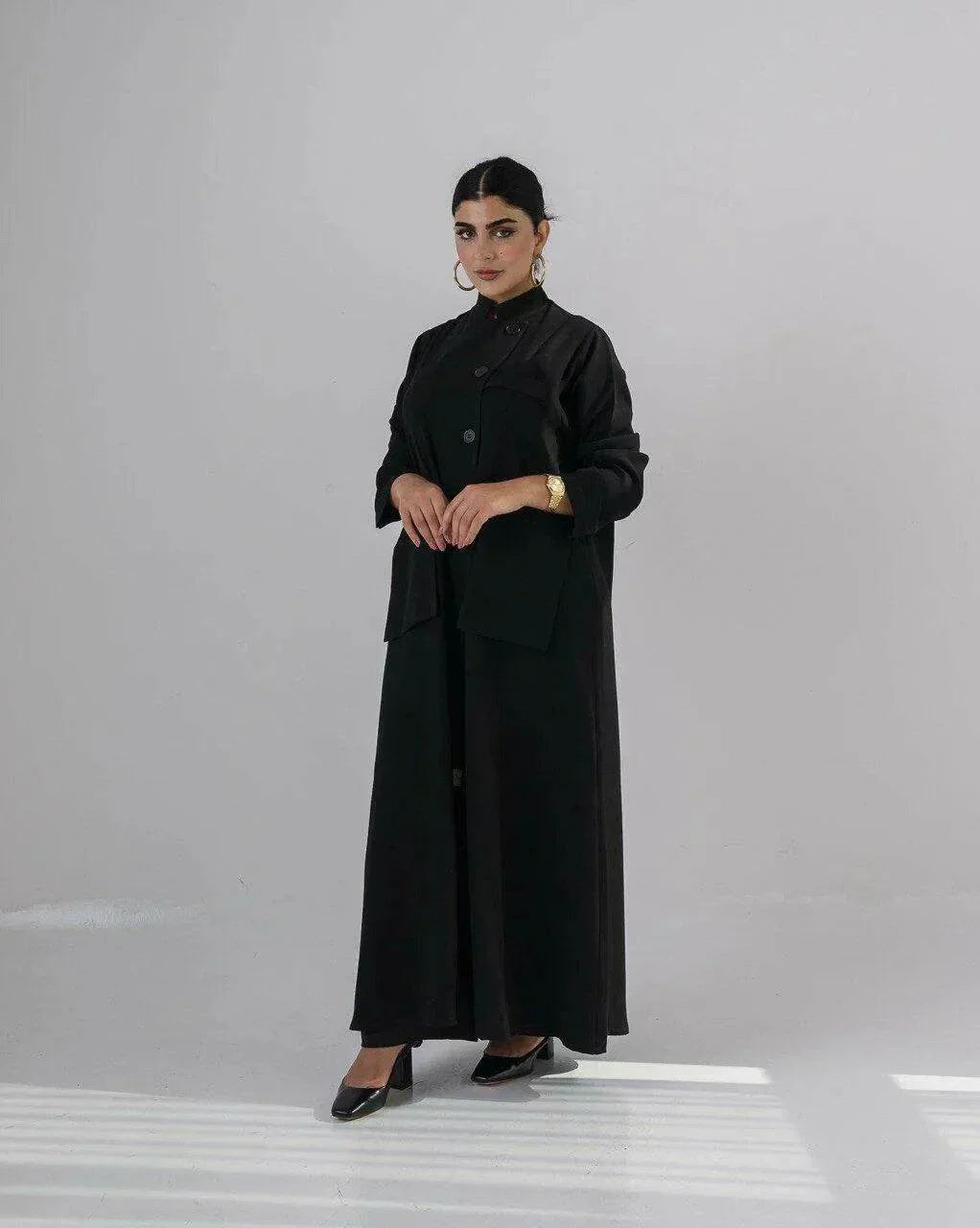 Woman wearing a sleek black crepe abaya with a Chinese collar and minimalist design.