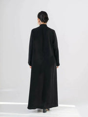 Woman wearing a sleek black crepe abaya with a Chinese collar and minimalist design.