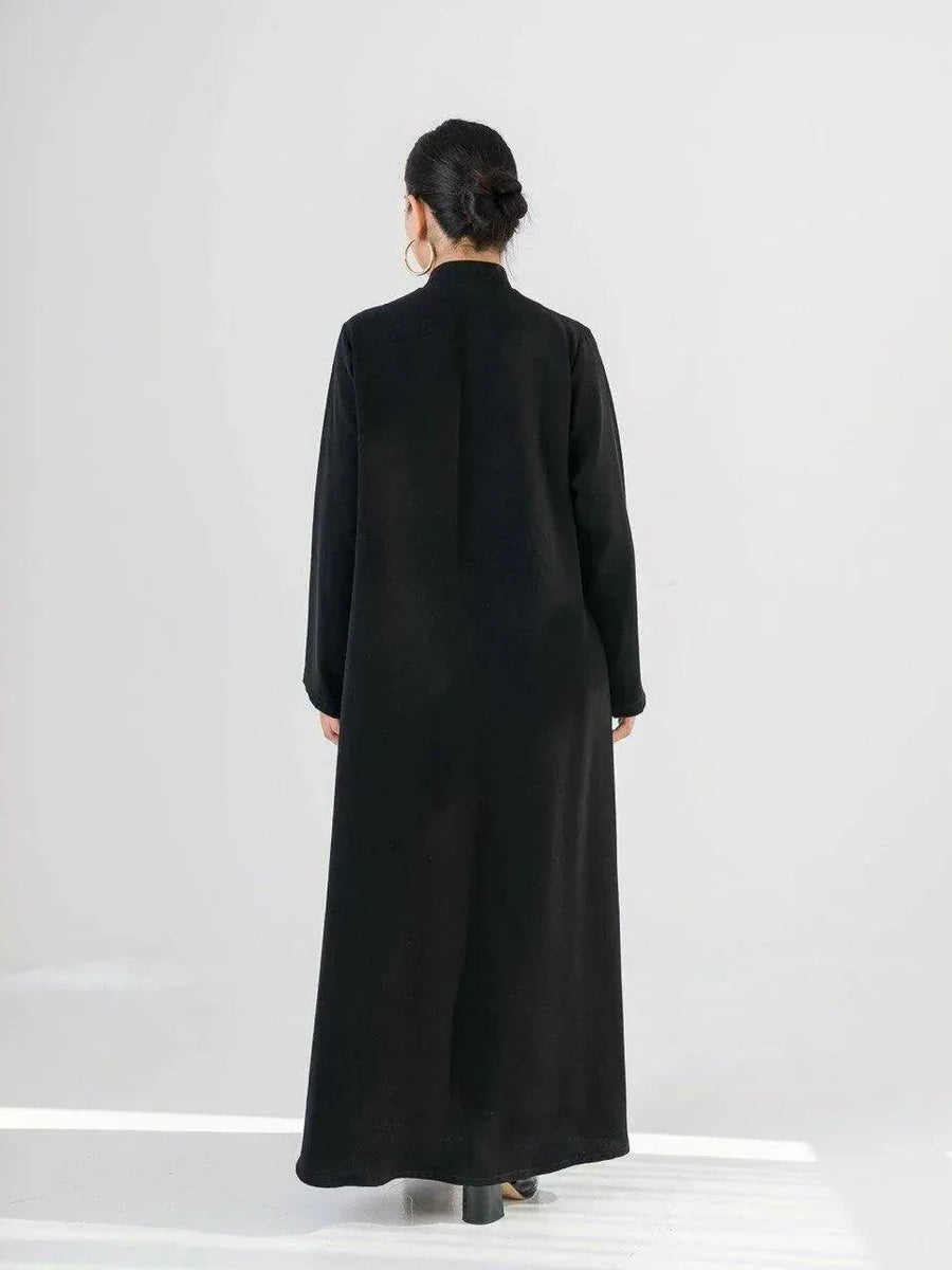 Woman wearing a sleek black crepe abaya with a Chinese collar and minimalist design.