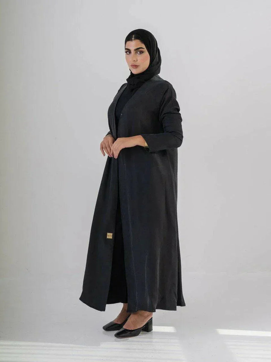 woman wearing luxurious black abaya made from soft cobra silk with elegant fluid drape and lightweight breathable fabric