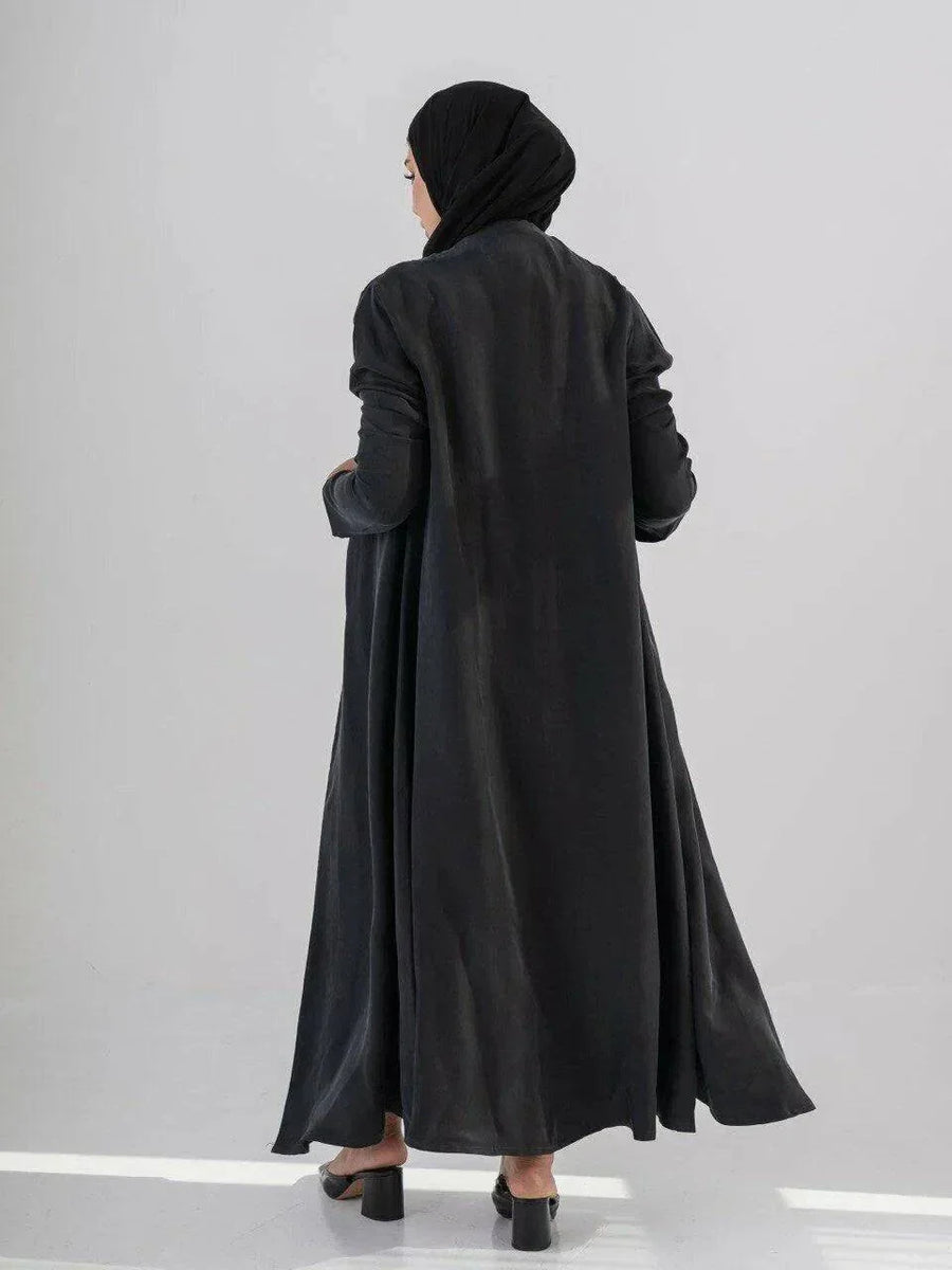 woman wearing luxurious black abaya made from soft cobra silk with elegant fluid drape and lightweight breathable fabric