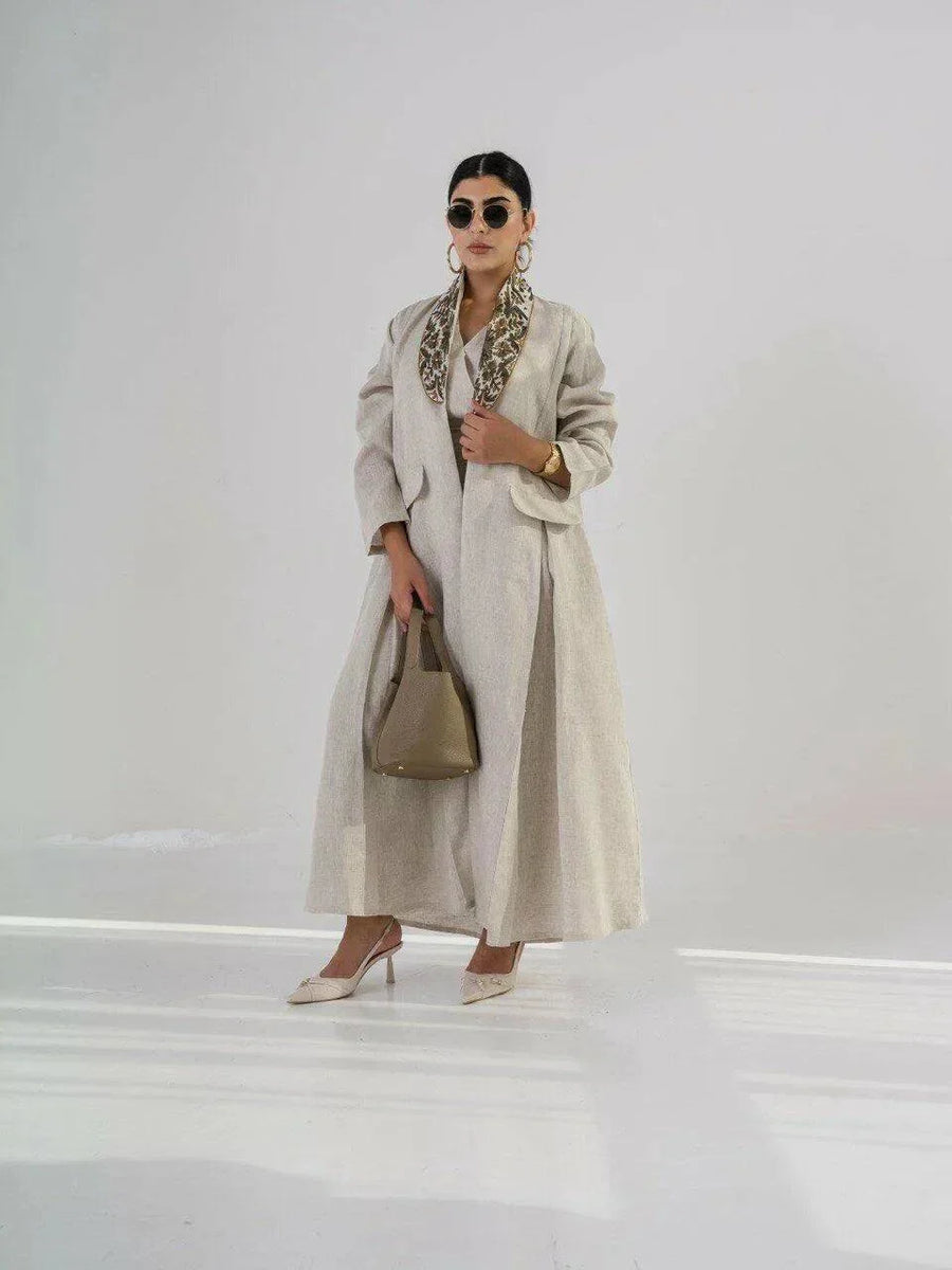 beige linen blazer-style abaya with floral embroidered collar and pleated pockets, styled for formal and everyday wear