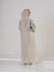Beige blazer-style abaya made from 100% natural linen with embroidered collar and pocket pleats, styled with heels and handbag.