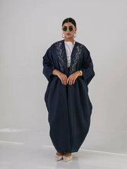 Woman wearing a deep navy lightweight linen abaya with navy blue floral embroidery and wide sleeves.