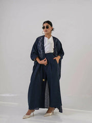 Woman wearing a deep navy lightweight linen abaya with navy blue floral embroidery and wide sleeves.