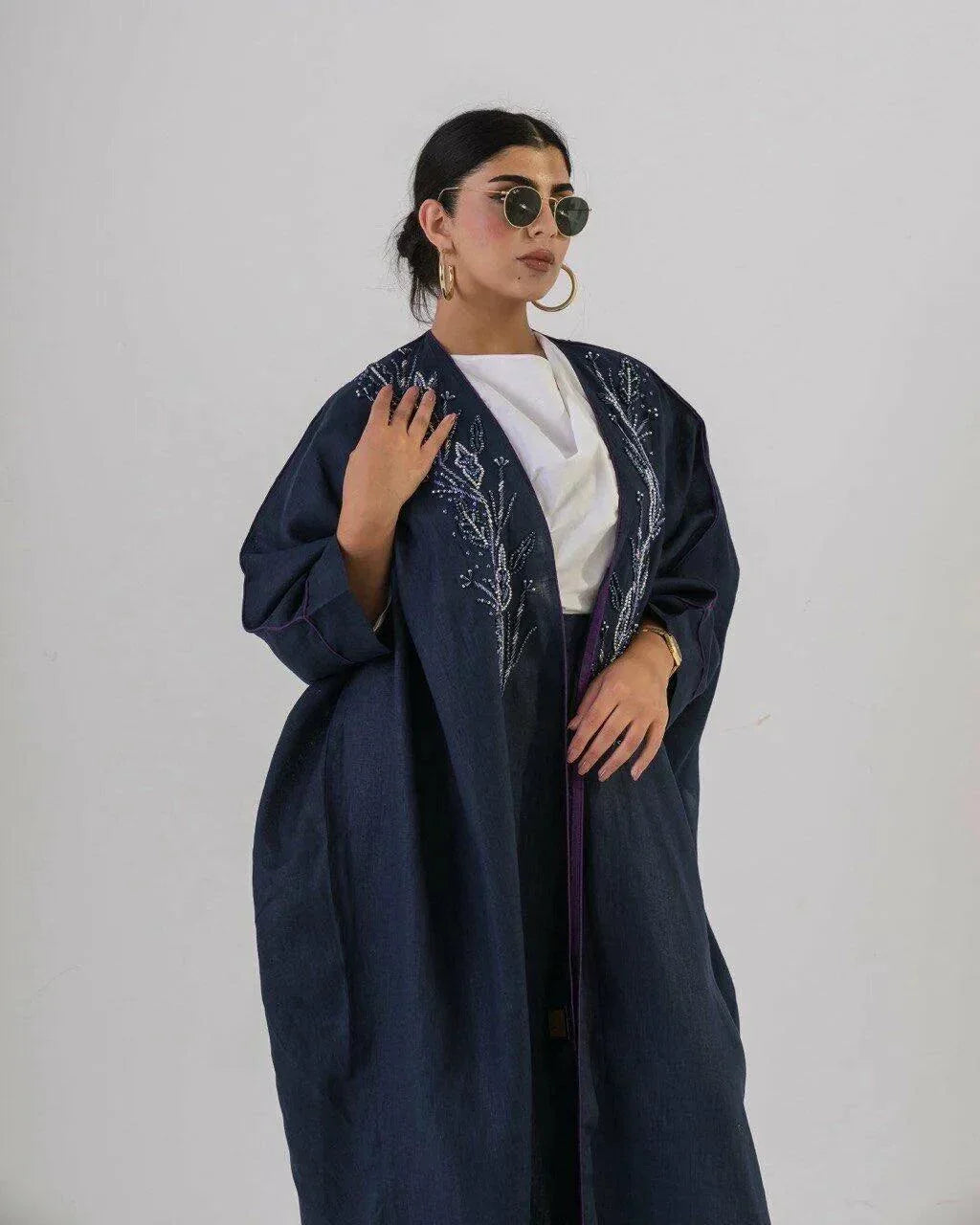 Woman wearing deep navy lightweight linen abaya with delicate blue floral embroidery and wide sleeves