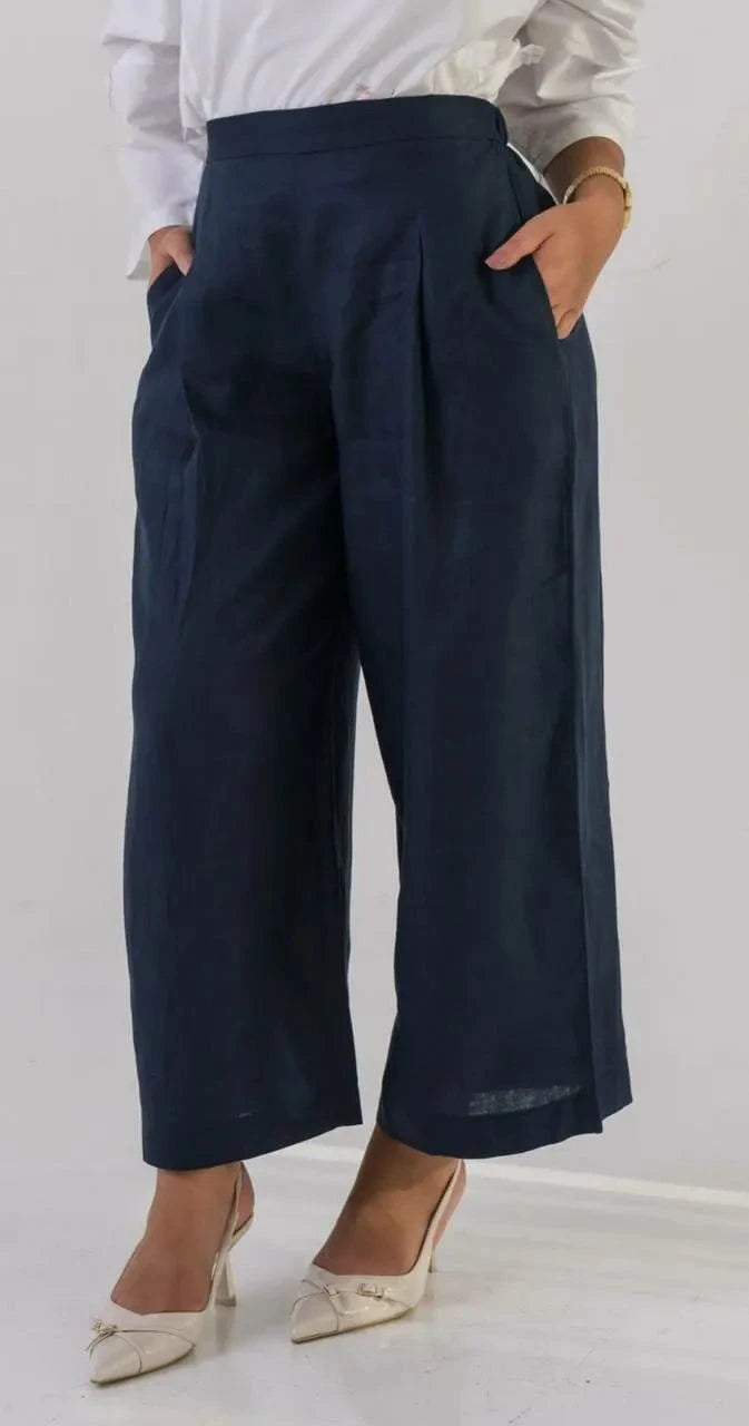 Women's linen navy blue wide-leg pants with pockets and pleats, styled with a white blouse and beige heels.
