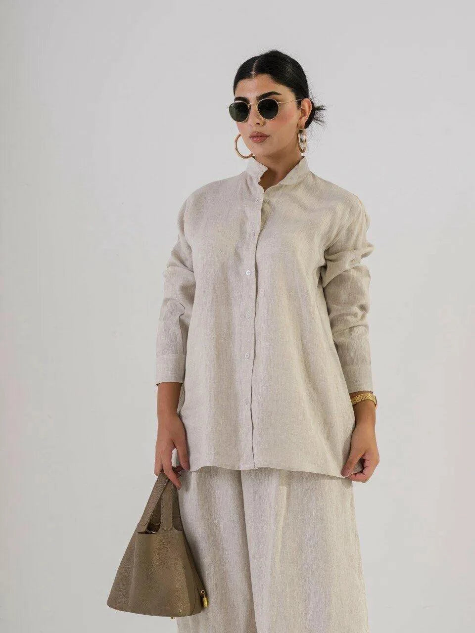 Woman wearing a linen beige blouse with a relaxed fit and natural texture, styled with matching pants and sunglasses