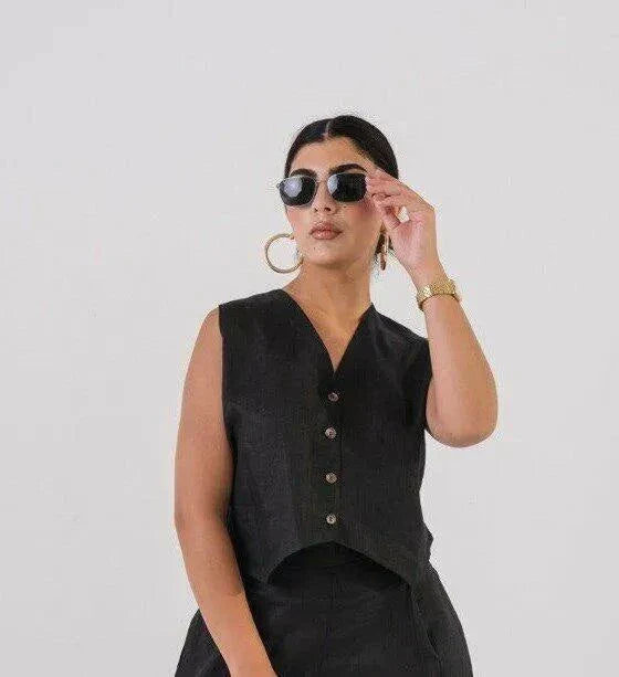 Woman wearing a short black linen vest with buttons, styled with sunglasses and gold accessories - Vest Black Linen