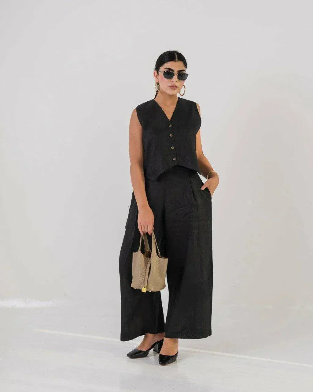 Woman wearing a short black linen vest with buttons, styled with sunglasses and gold accessories - Vest Black Linen