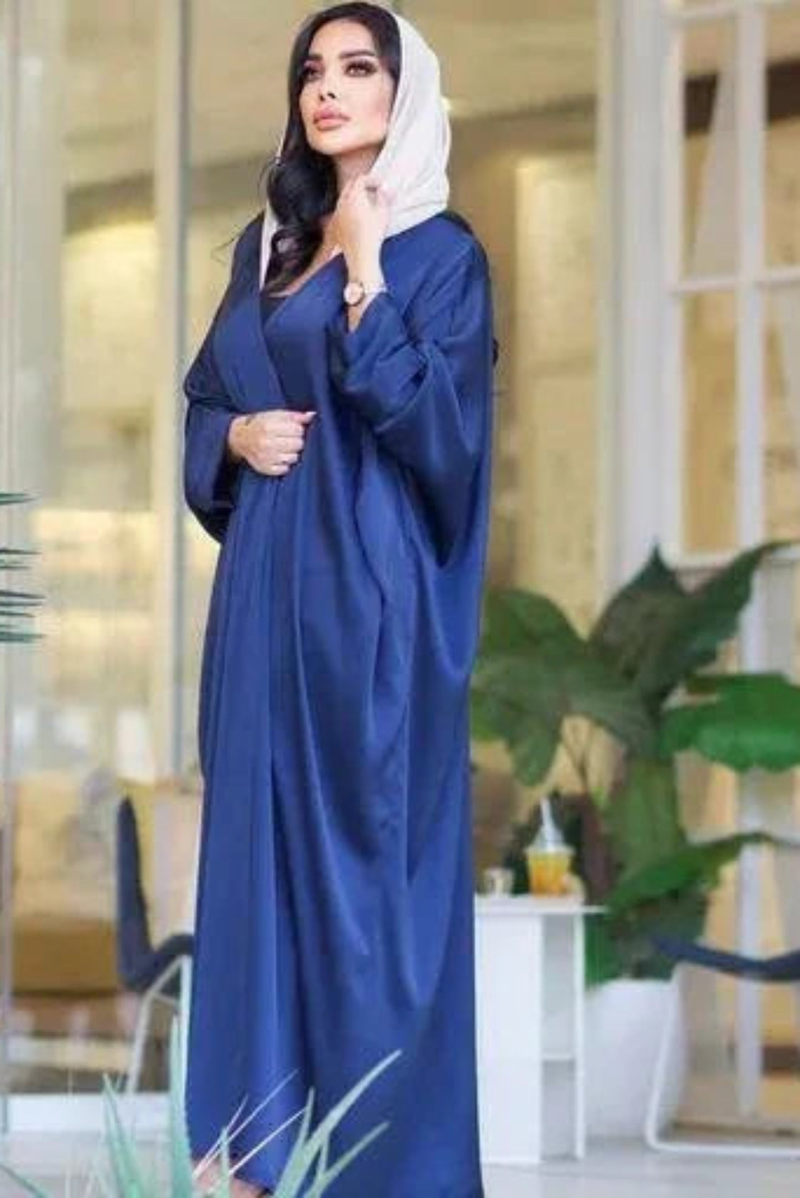 woman wearing flowing navy blue bisht with soft sheen and drape standing indoors