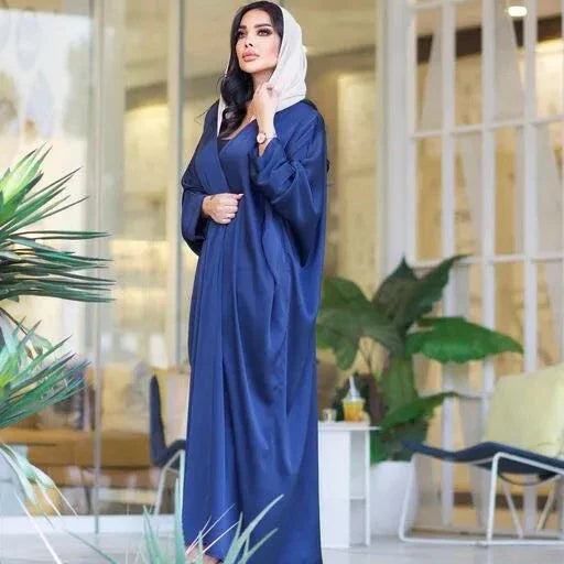 woman wearing flowing navy blue bisht with soft sheen and drape standing indoors