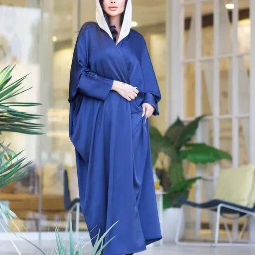 woman wearing flowing navy blue bisht with soft sheen and drape standing indoors