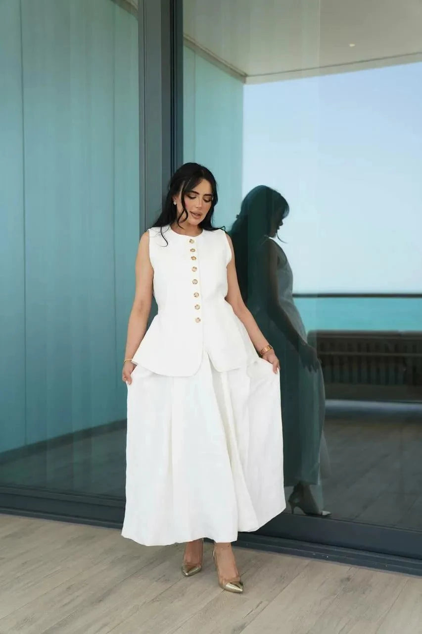 Woman wearing off-white linen skirt with flowy silhouette standing by glass wall reflecting sea view