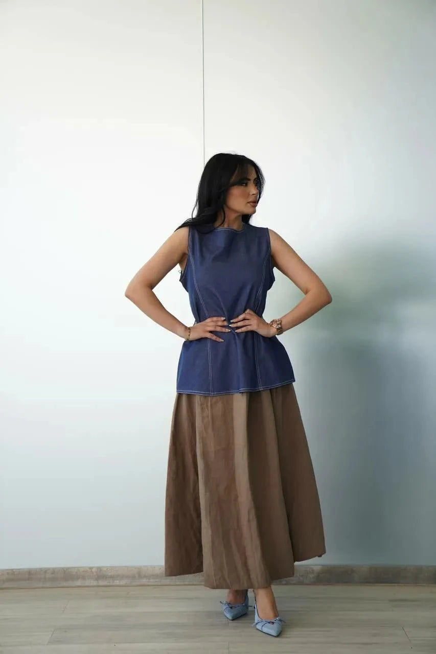 Woman wearing a breezy linen brown skirt with a relaxed silhouette and a sleeveless navy top.