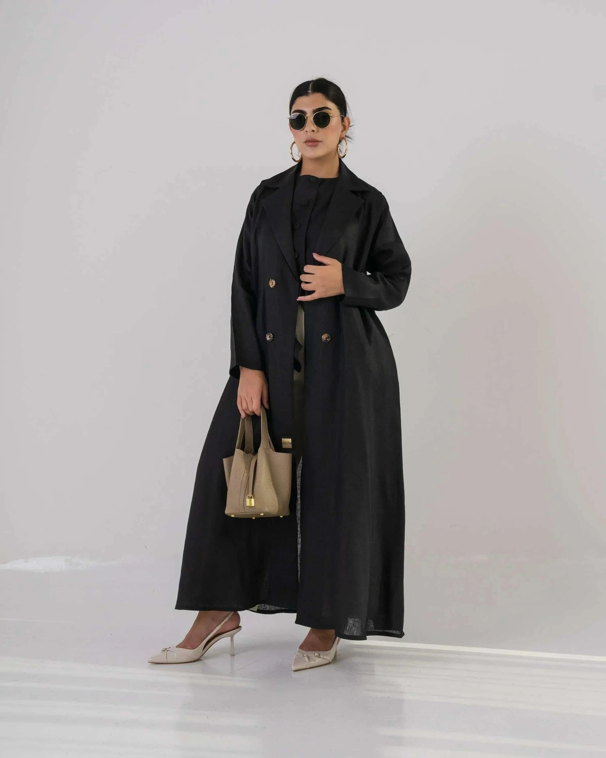 woman wearing black minimal linen blazer with clean silhouette and lightweight fabric carrying beige handbag and wearing sunglasses