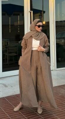 woman wearing beige abaya with relaxed silhouette holding white handbag outdoors