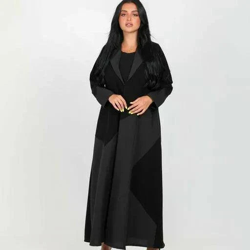Woman wearing a full-length statement black blazer abaya with geometric crepe fabric panels and a sharp lapel collar