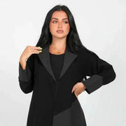 Woman wearing a full-length statement black blazer abaya with geometric crepe fabric panels and a sharp lapel collar