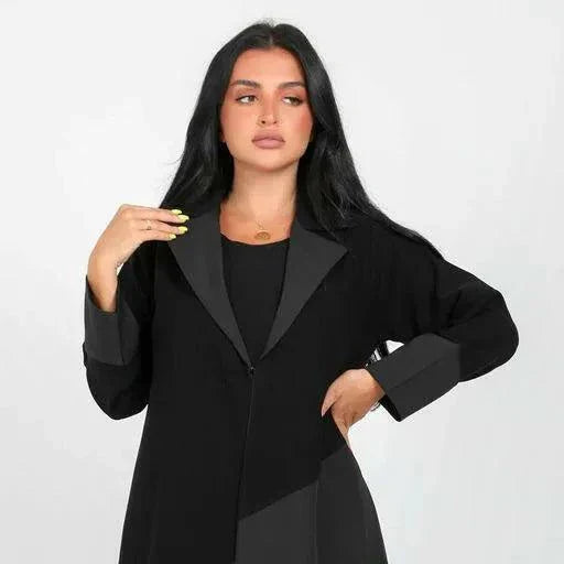 Woman wearing a full-length statement black blazer abaya with geometric crepe fabric panels and a sharp lapel collar