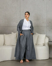 woman wearing gray crumpled linen relaxed-fit outerwear with matching pants and white shirt indoors