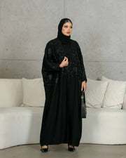 Elegant black crepe abaya with subtle black floral embellishment for a sophisticated evening look