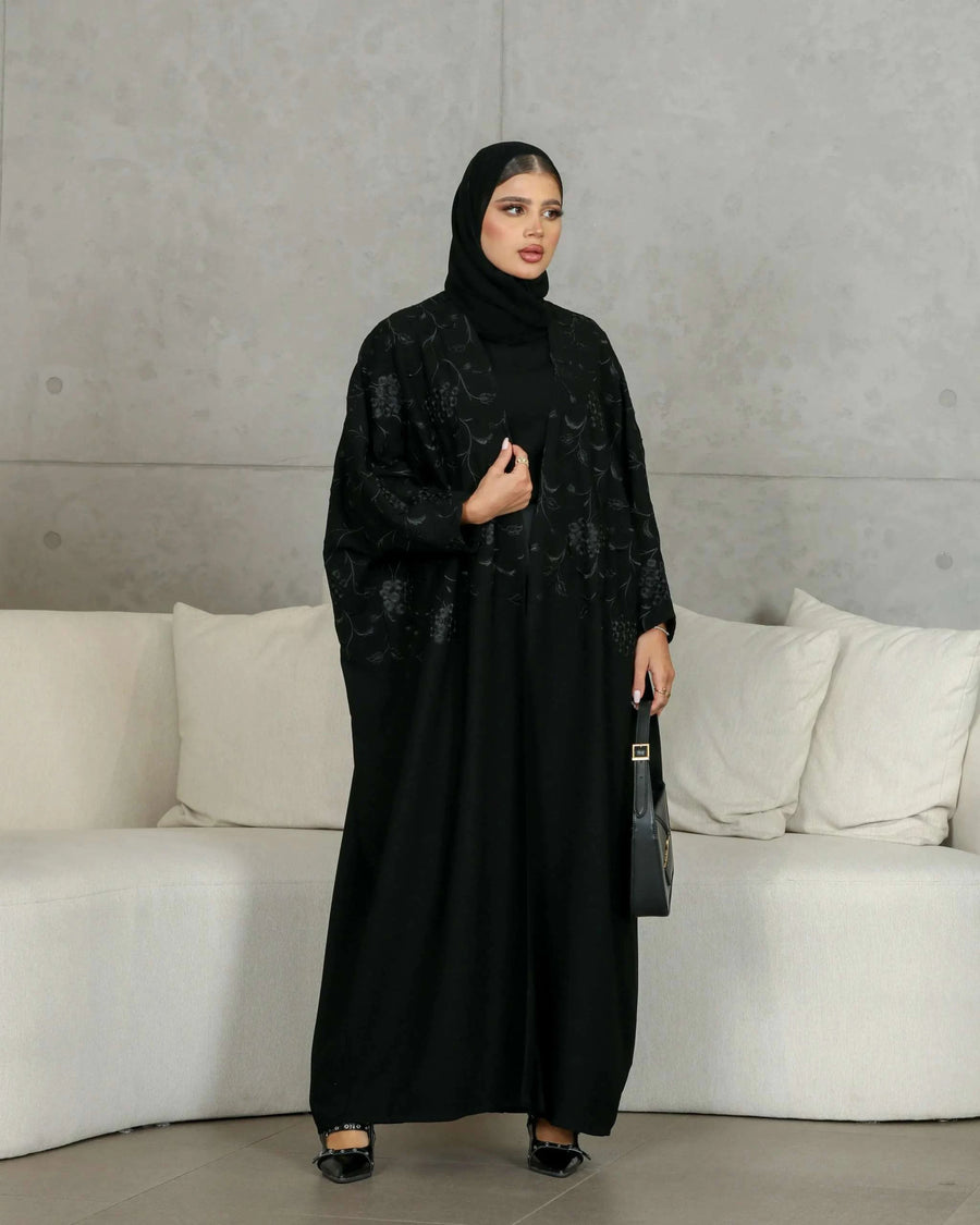 Elegant black crepe abaya with subtle black floral embellishment for a sophisticated evening look