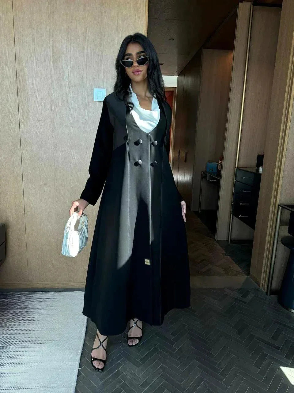 Modern black abaya with layered blazer-style design, wide lapels, and double-breasted buttons, styled for elegant daywear or evening outings