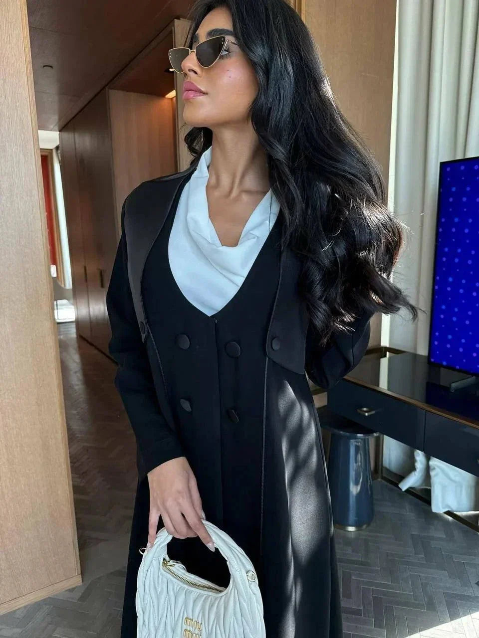 Modern black abaya with layered blazer-style design, wide lapels, and double-breasted buttons, styled for elegant daywear or evening outings