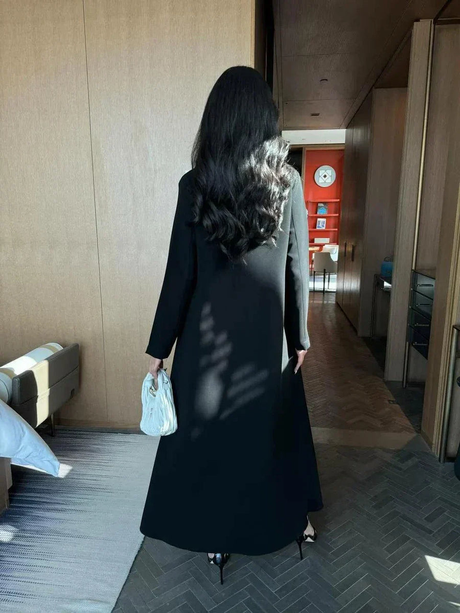 Modern black abaya with layered blazer-style design, wide lapels, and double-breasted buttons, styled for elegant daywear or evening outings