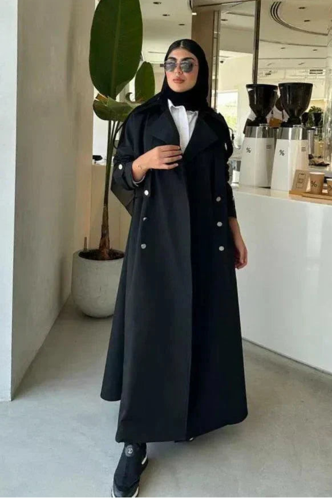 Modern black abaya with trench coat design, wide lapels, double-breasted silver buttons, and cuff details for a sophisticated look.