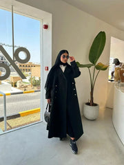 Modern black abaya with trench coat design, wide lapels, double-breasted silver buttons, and cuff details for a sophisticated look.