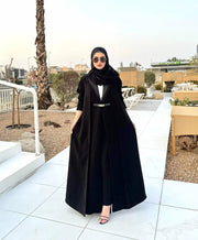 woman wearing chic black crepe and mokado fabric blazer with matching waist belt and sunglasses standing outdoors - chic blazer