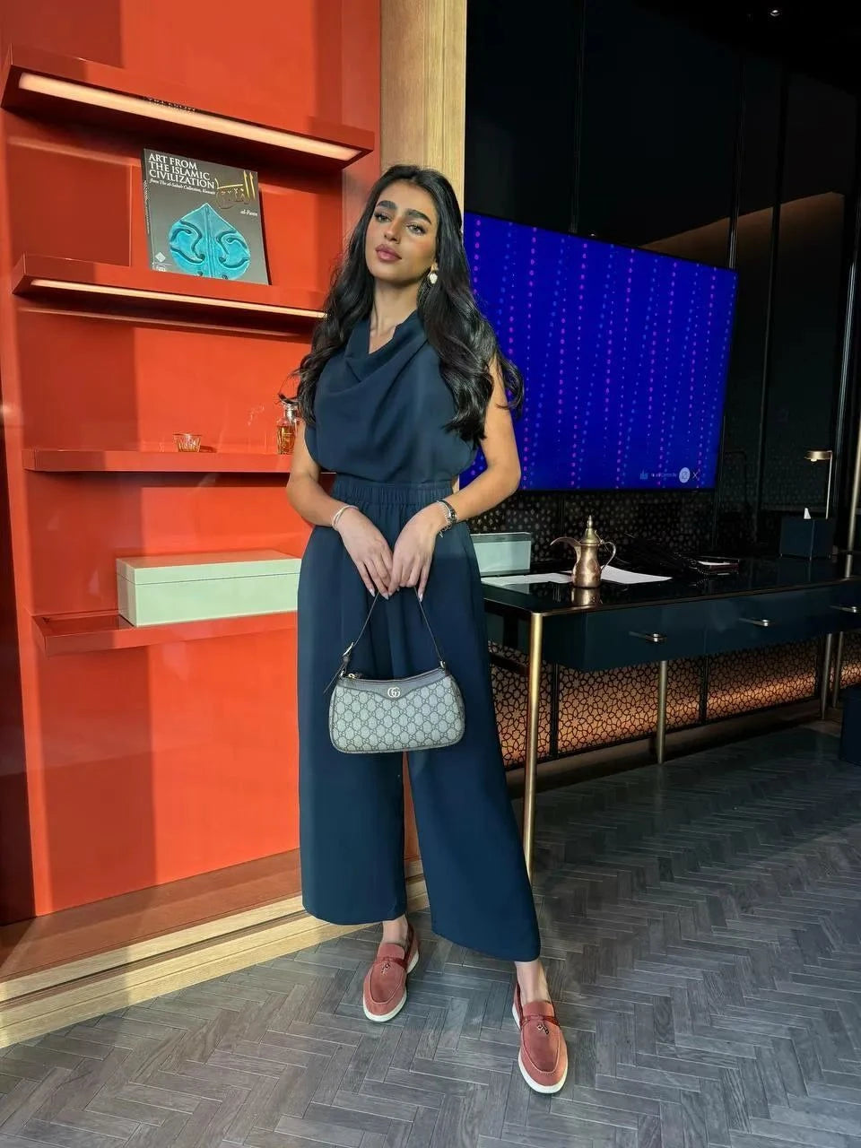 woman wearing elegant navy blue crepe abaya with flowy silhouette holding handbag indoors