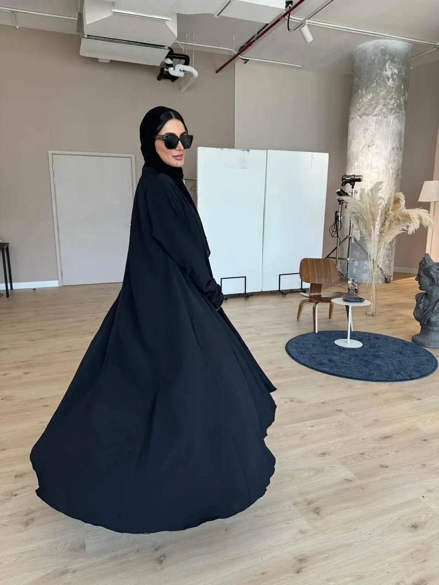 Woman wearing Lazra classic black patterned crepe abaya with elegant drape in modern indoor setting