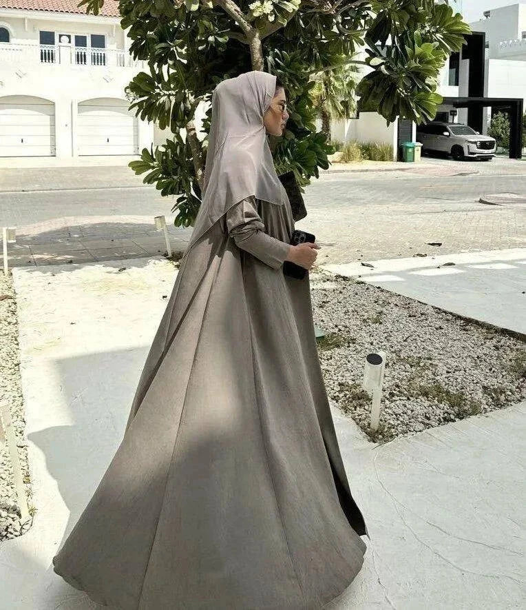 Velma abaya in dark beige light crepe with subtle texture and elegant natural tone worn with matching hijab and white pants