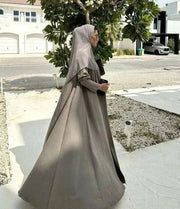 Velma abaya in dark beige light crepe with subtle texture and elegant natural tone worn with matching hijab and white pants