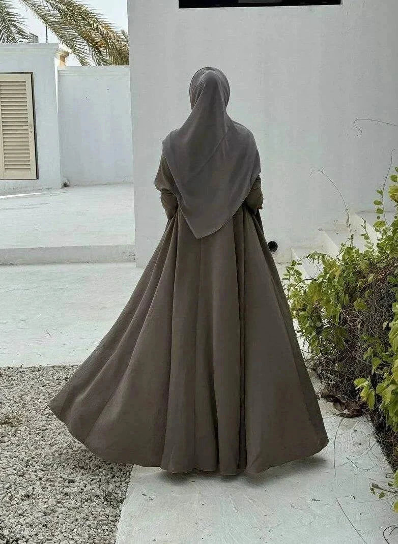 Velma abaya in dark beige light crepe with subtle texture and elegant natural tone worn with matching hijab and white pants