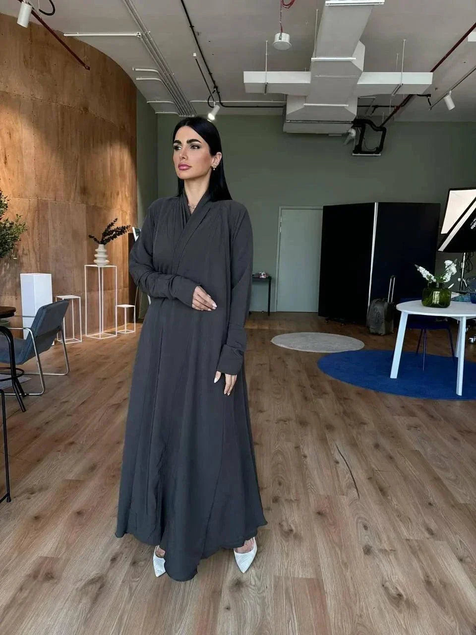 woman wearing flowing dark olive abaya in modern room with wooden floor - light olive abaya