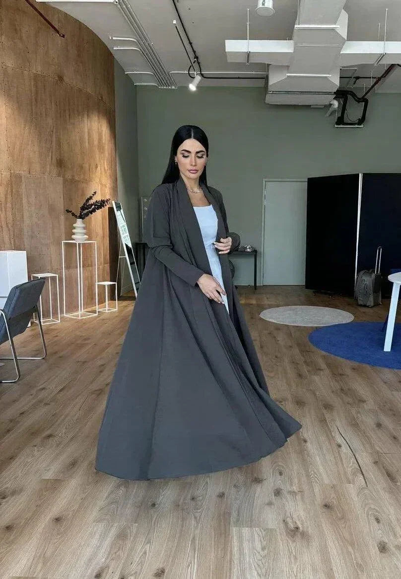 woman wearing flowing dark olive abaya in modern room with wooden floor - light olive abaya