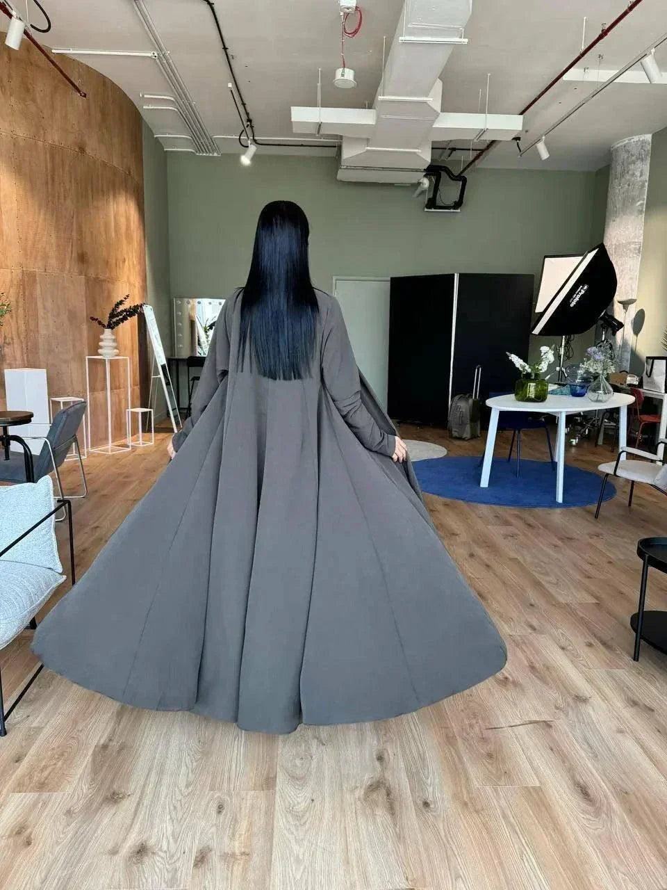 woman wearing flowing dark olive abaya in modern room with wooden floor - light olive abaya