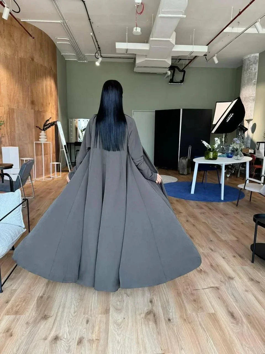 woman wearing flowing dark olive abaya in modern room with wooden floor - light olive abaya