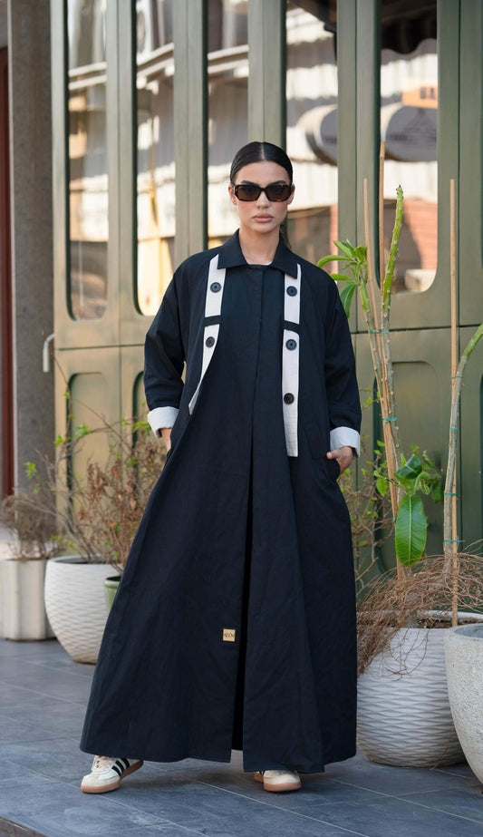 black blazer-style abaya with trench coat fabric, functional pockets, and button detail, worn with sunglasses