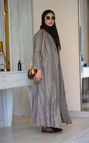 woman wearing relaxed brown abaya made of crumpled linen with cappuccino shade, accessorized with sunglasses and brown handbag