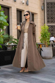 Woman Woman wearing a long coffee chino coat with tailored fit and sunglasses in an outdoor urban settingwearing a long coffee-colored chino coat with tailored fit and sunglasses in an outdoor urban setting