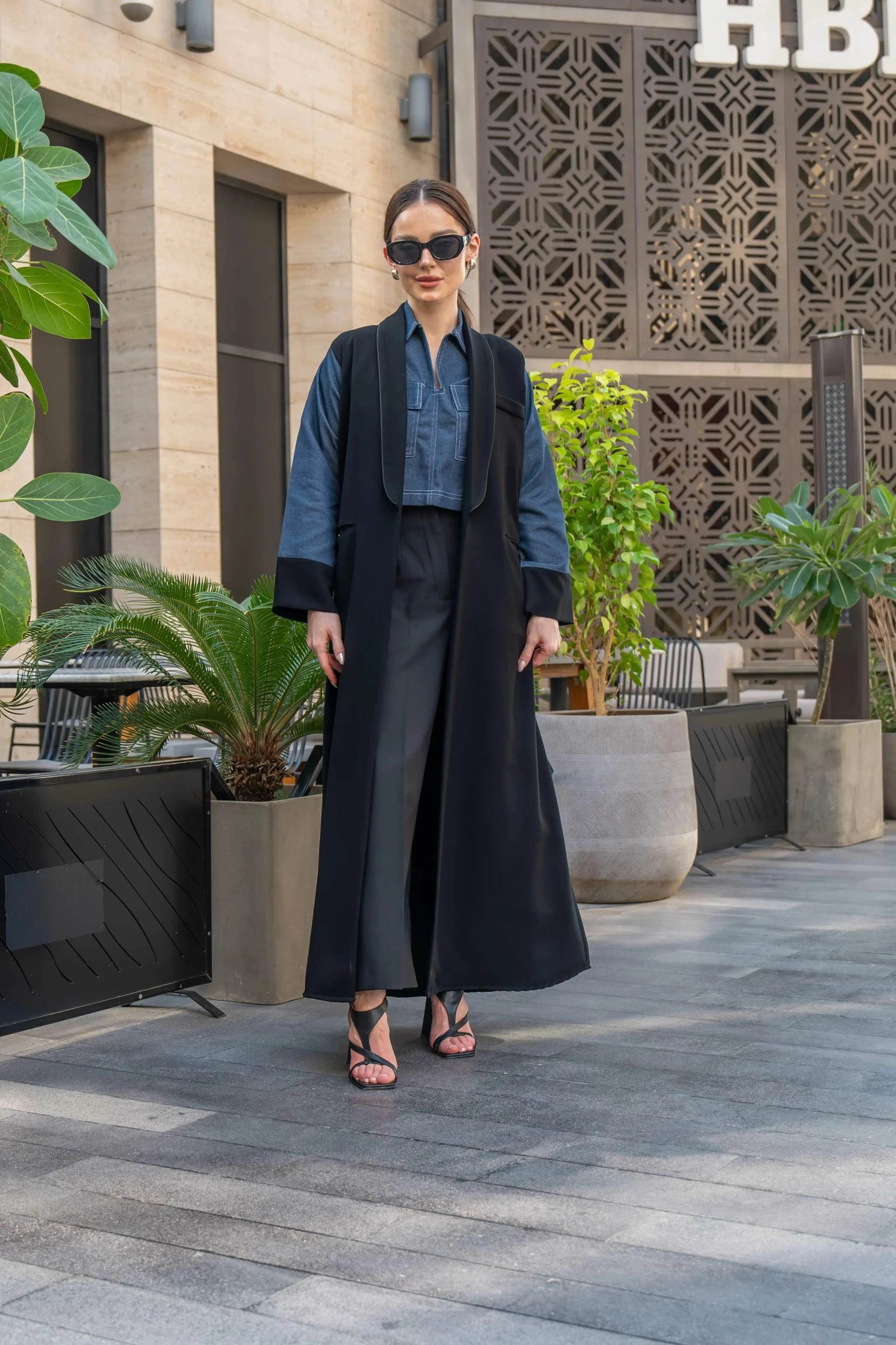 woman wearing jeans-blue cropped blouse with black wide-leg pants and black long vest outdoors