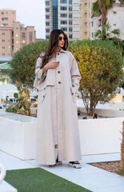 Woman wearing beige Sandline free-size trench coat with front buttons and flap pockets outdoors