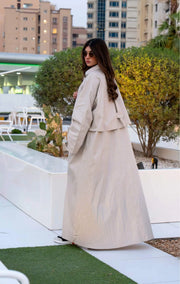 Beige Sandline chino trench coat with wide storm flap, front buttons, and flap pockets in relaxed fit for layering over casual or abaya outfits